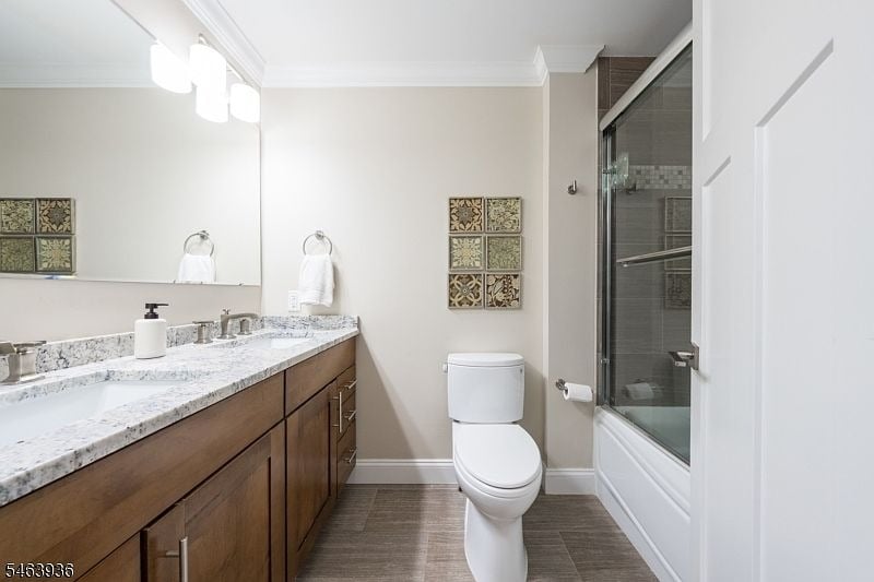 Bathroom with a double vanity, dark wood cabinets, and a glass-enclosed tub and shower.