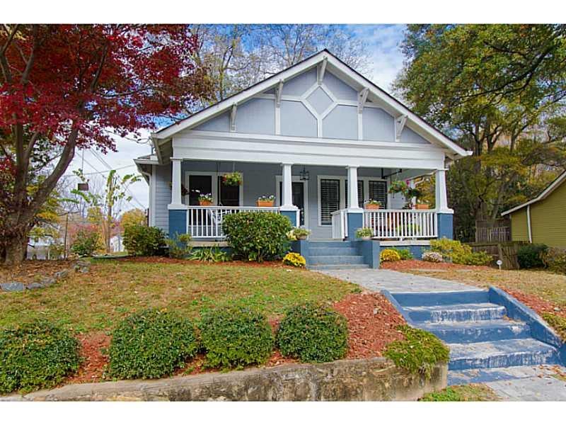 Blue-and-white house with a covered porch, blue front steps, and autumn trees.
