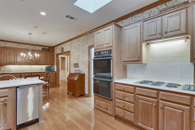Kitchen with light wood cabinetry, double ovens, a large island, and a cooktop.