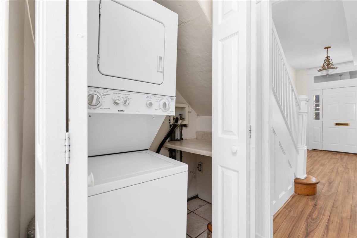 Stacked washer and dryer in a closet beside the wood-floored entry hall and staircase.