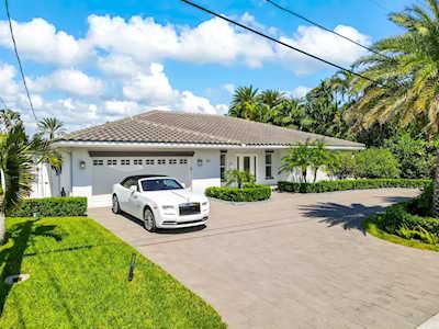 Single-story home with a tiled roof, white garage doors, and a white car in the driveway.
