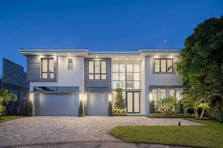 Modern two-story home with a broad driveway, double garage, and illuminated windows at dusk.