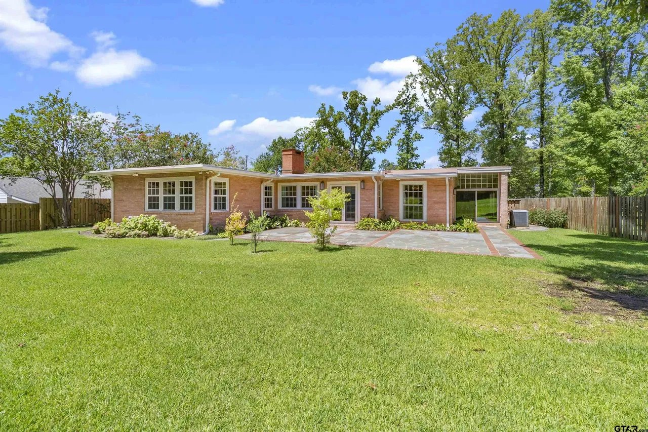 photo of back patio of house with windows and lightred/brown brick and a grey stone patio