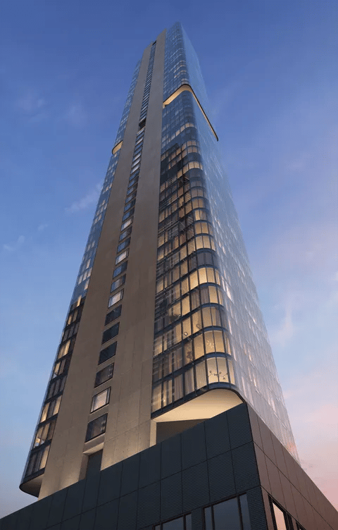 The Greenwich's curved glass tower rises above its dark stone base at dusk.