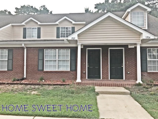 A charming brick house featuring a welcoming sign that reads "Home Sweet Home."