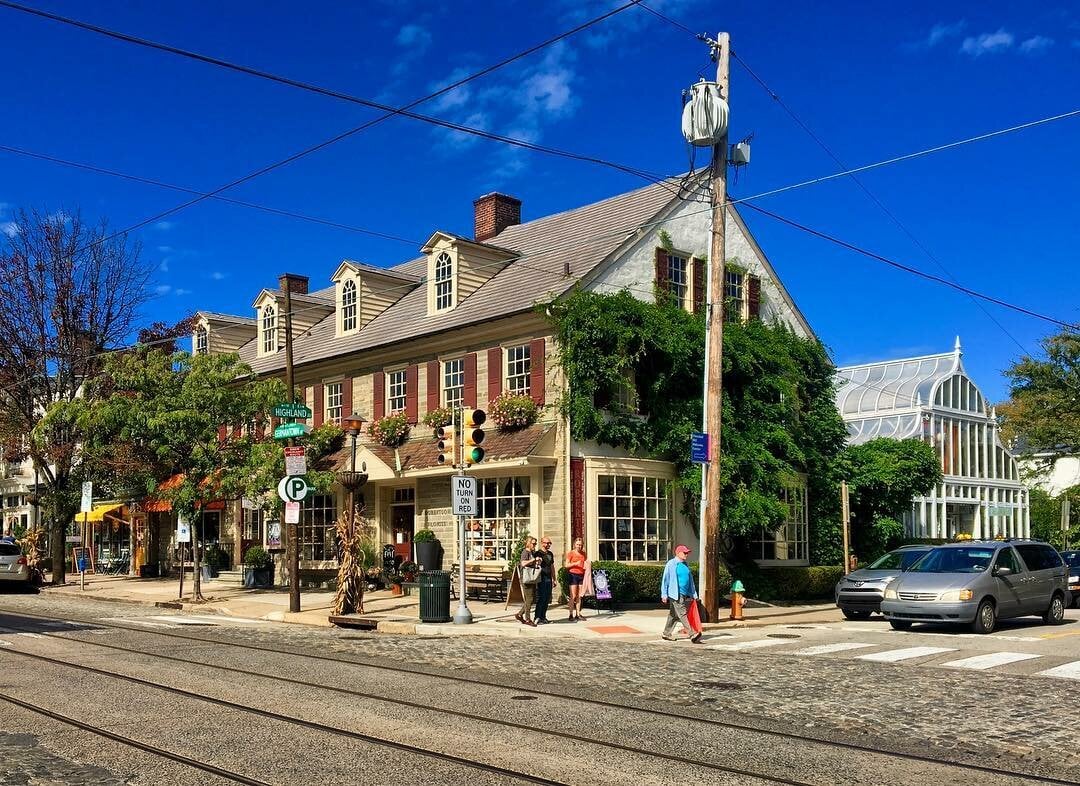 Historic stone building with red shutters and dormer windows beside a glass conservatory.