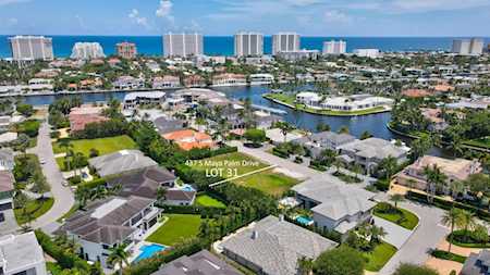 Aerial view of East Boca homes and waterways, with the ocean and high-rise skyline beyond.