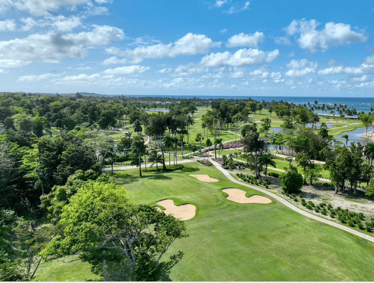 Aerial view of a coastal golf course with palm-lined fairways and ocean beyond.