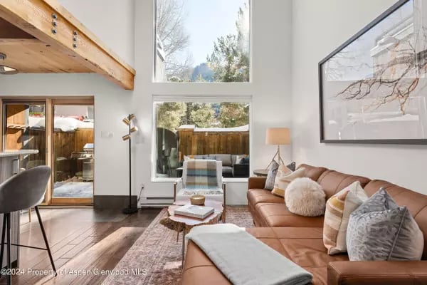 Living room with a vaulted ceiling, tall windows, and a tan leather sofa.