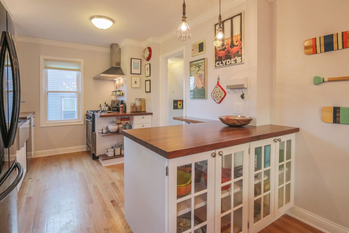 Kitchen with a large dark wood island, glass-front cabinets, and stainless-steel range.