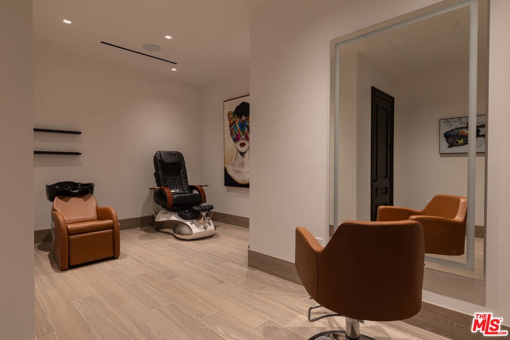 Furnished salon with brown leather chairs, a black pedicure chair, and a large wall mirror.