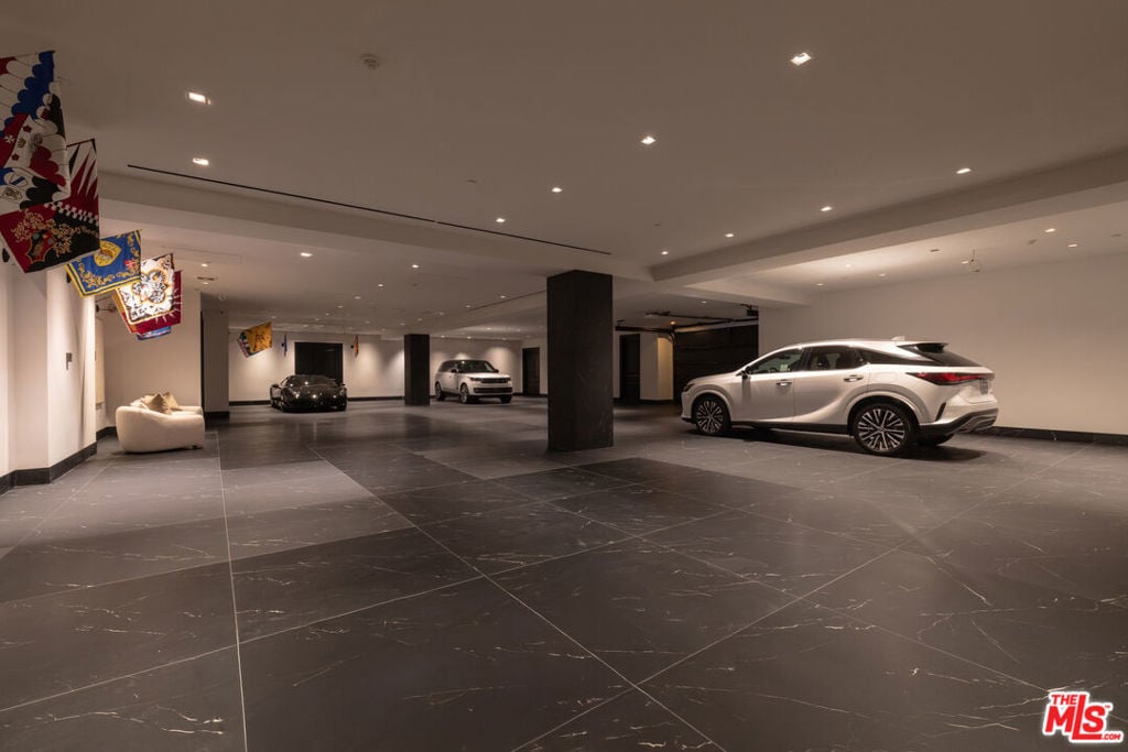 Spacious tiled garage with three parked cars and colorful flags.