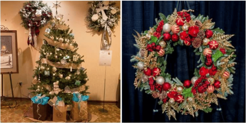Lit Christmas tree with gift bags beside a festive wreath display.