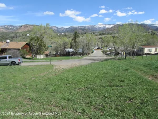 Grassy lot overlooking a residential street and mountain range in Collbran.
