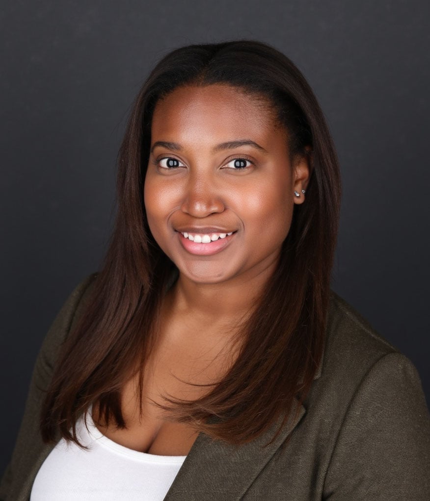 Elle Williams smiling in a dark olive blazer and white top.