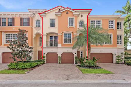Attached peach townhomes with arched entryways and garages; a red outline marks the central unit.