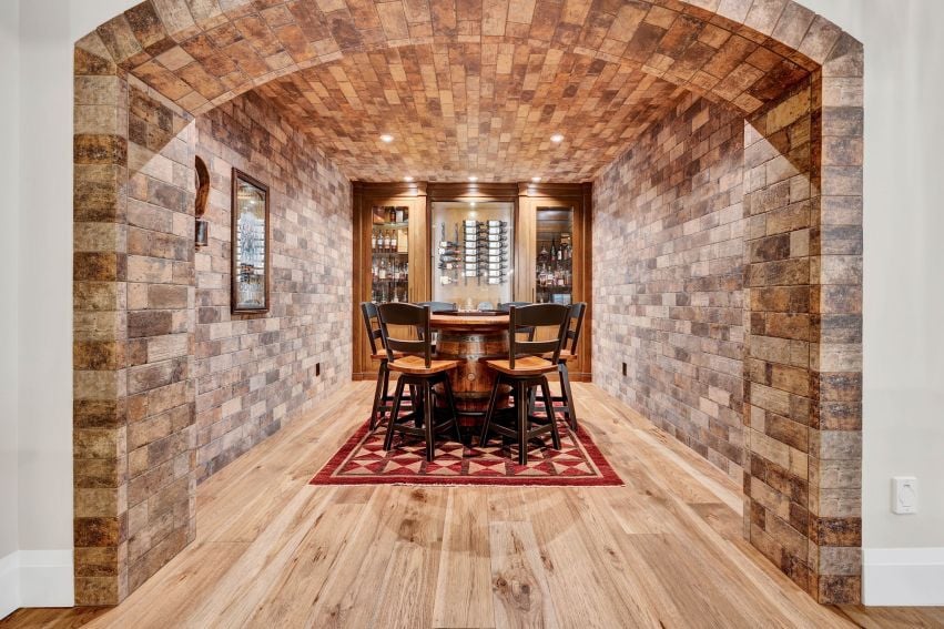 Wine cellar with a brick-vaulted ceiling, stone walls, and a round tasting table.