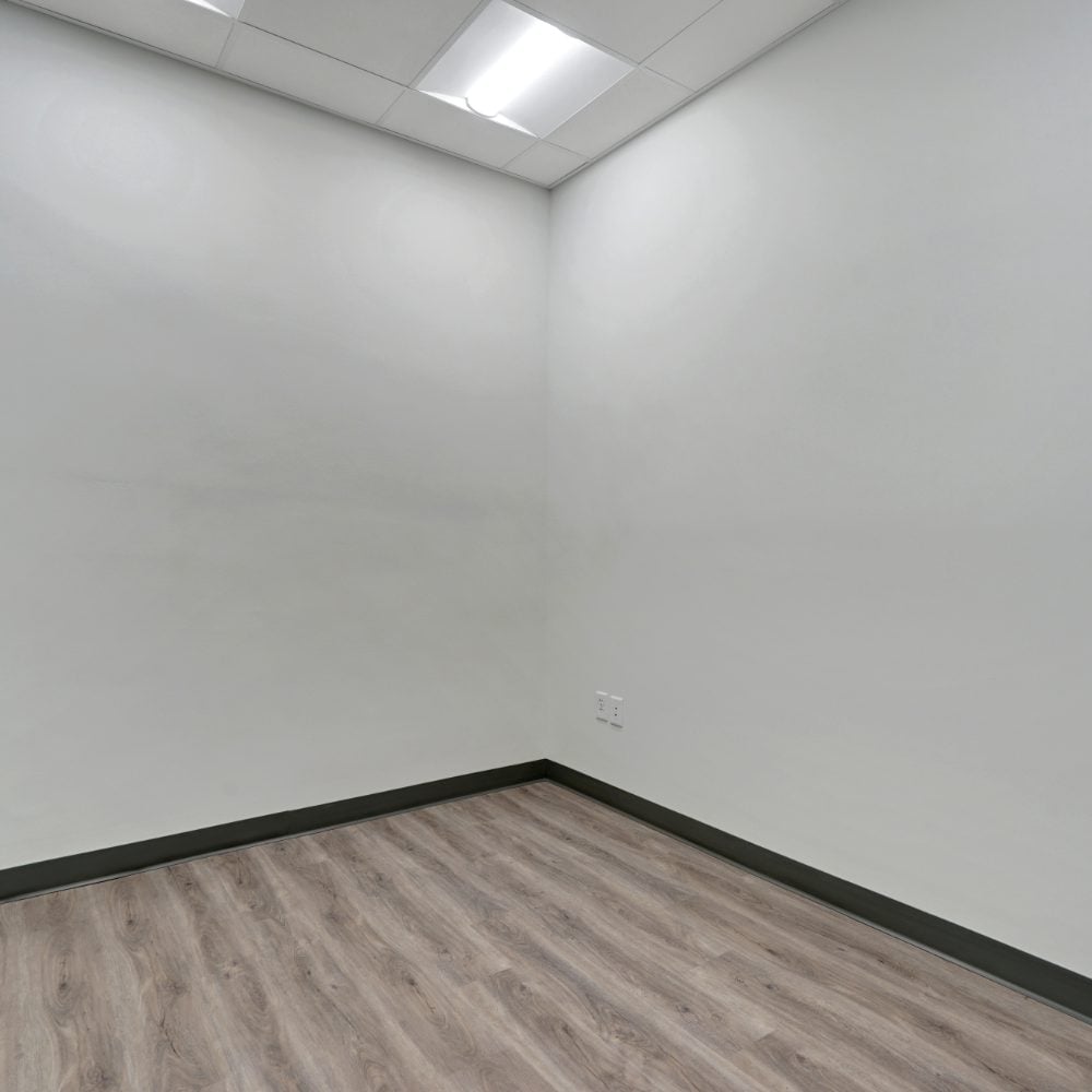 Vacant room with wood-look flooring, white walls, and a suspended ceiling.