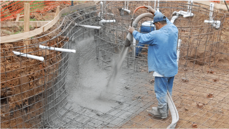 A worker sprays concrete over rebar during construction.