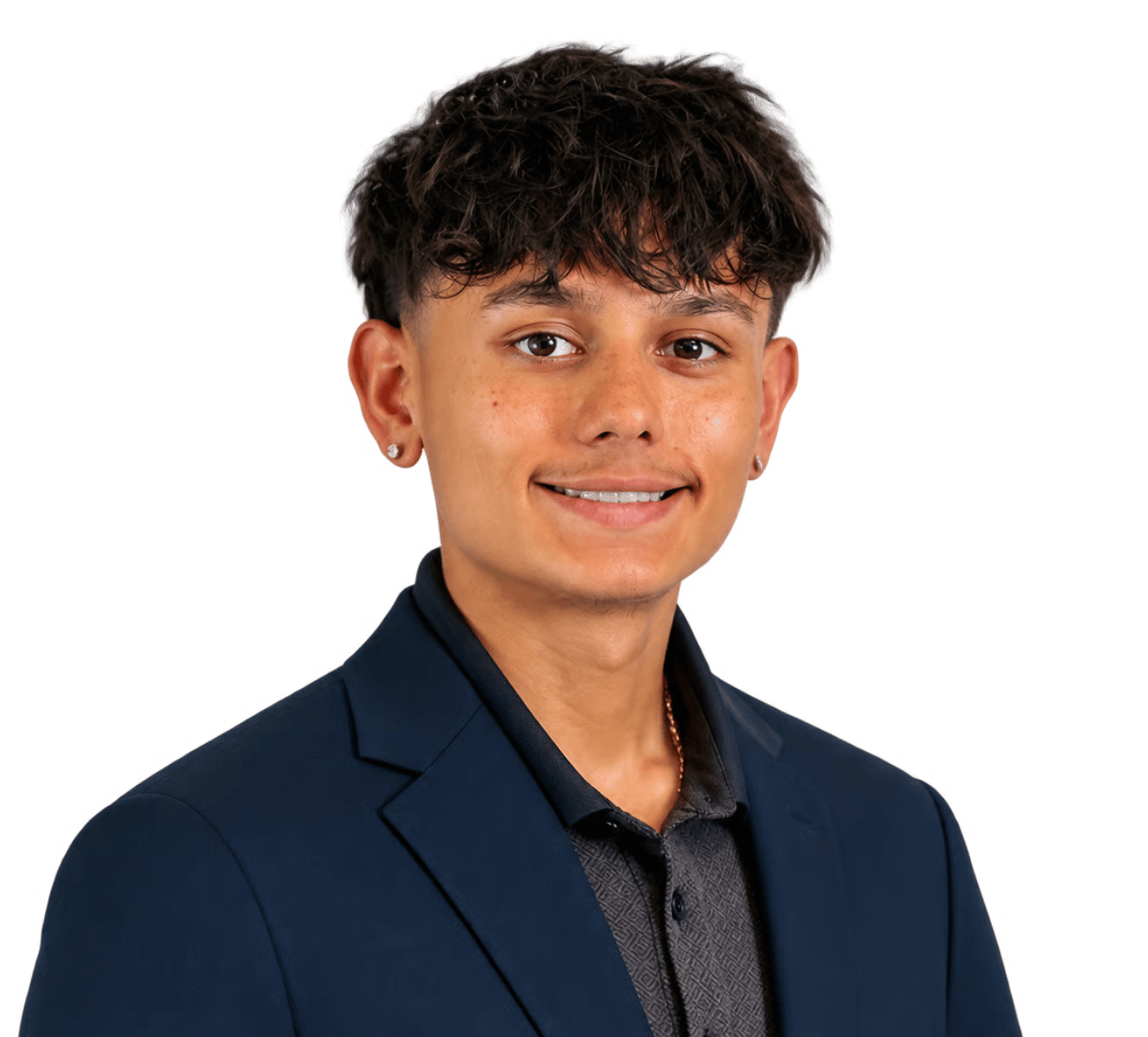 Damian Ramirez smiling in a navy blazer and dark patterned shirt.