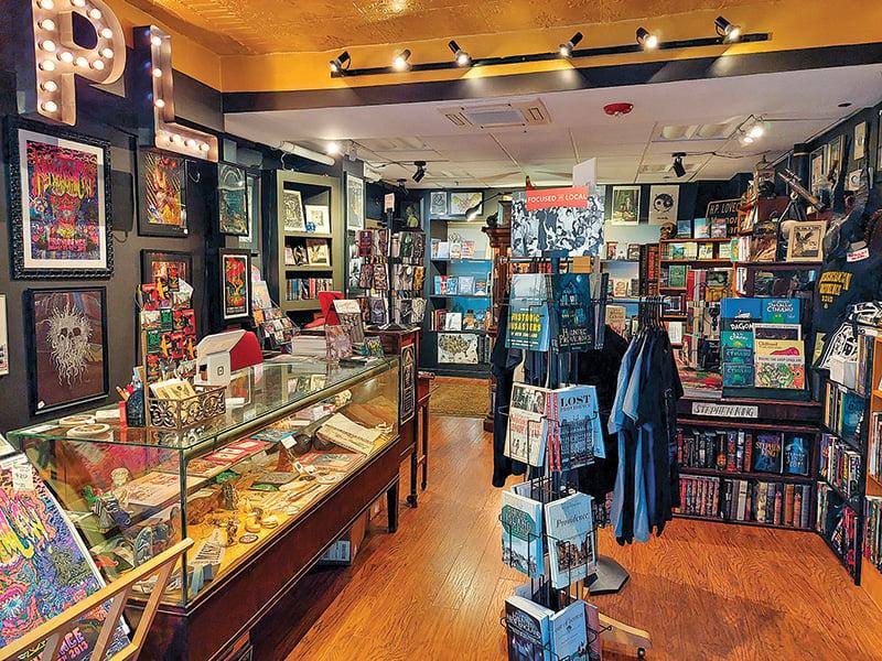 Bookstore interior with crowded bookshelves, a glass display counter, and wooden floors.