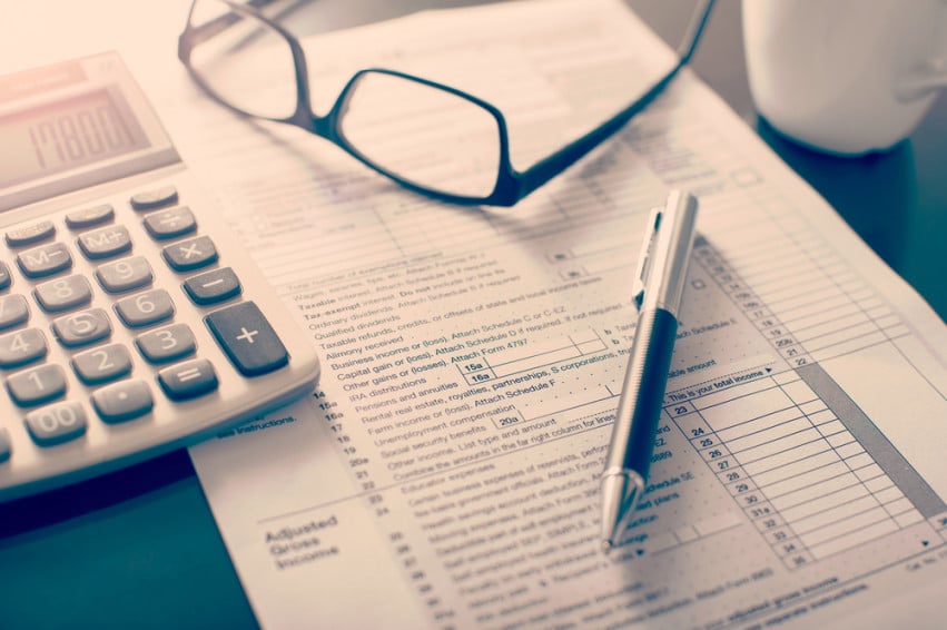 Financial paperwork with a calculator, eyeglasses, and pen.