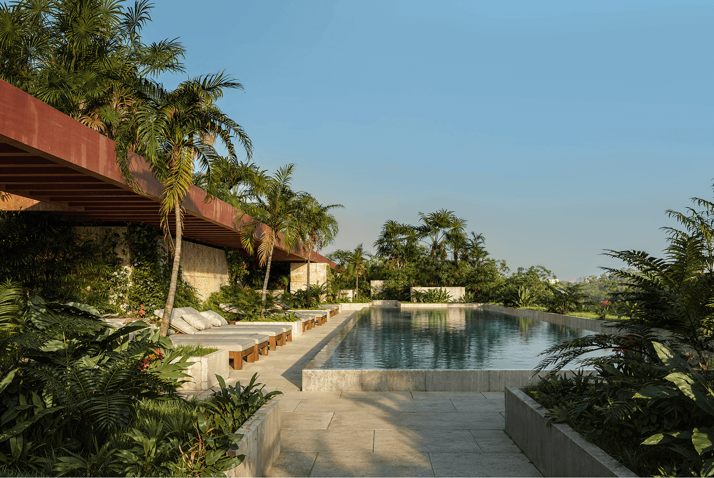 Residential development pool bordered by tropical landscaping and cushioned loungers.