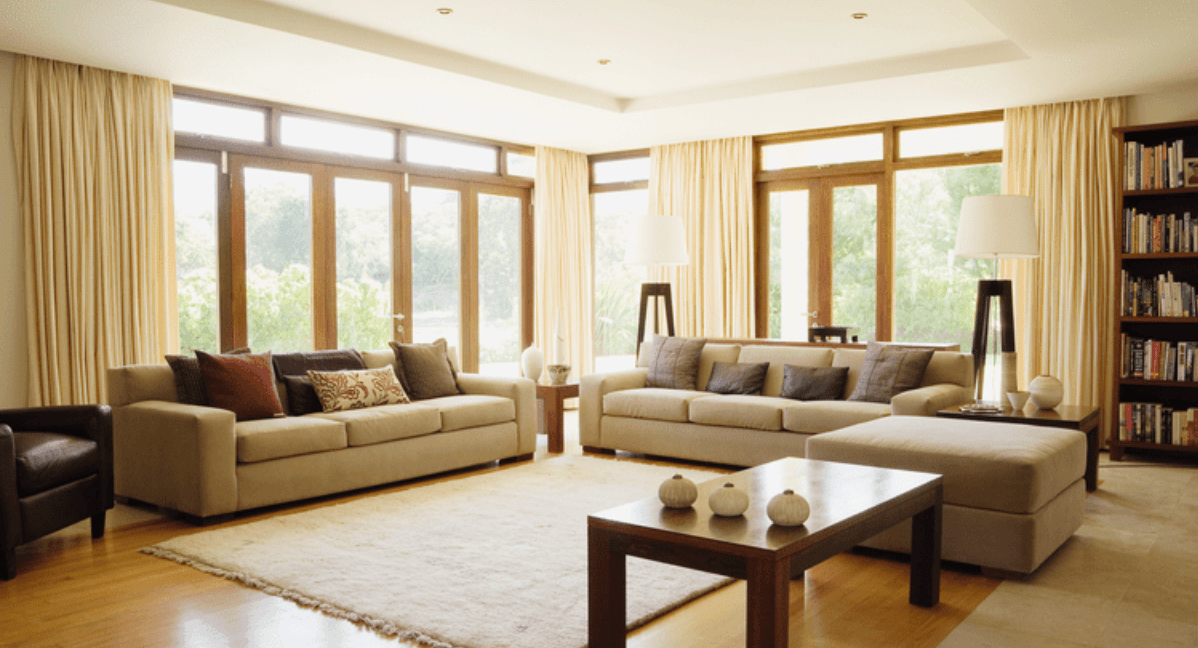 Living room with beige sofas, a wood coffee table, and tall curtained windows.