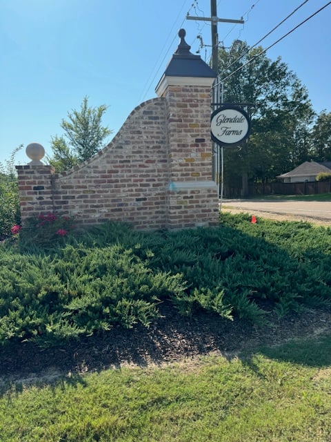 Brick Glendale Farms entrance monument with an oval sign and landscaped shrubs.