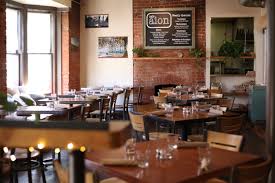 Aion restaurant dining room with brick walls, wooden tables, and large windows.