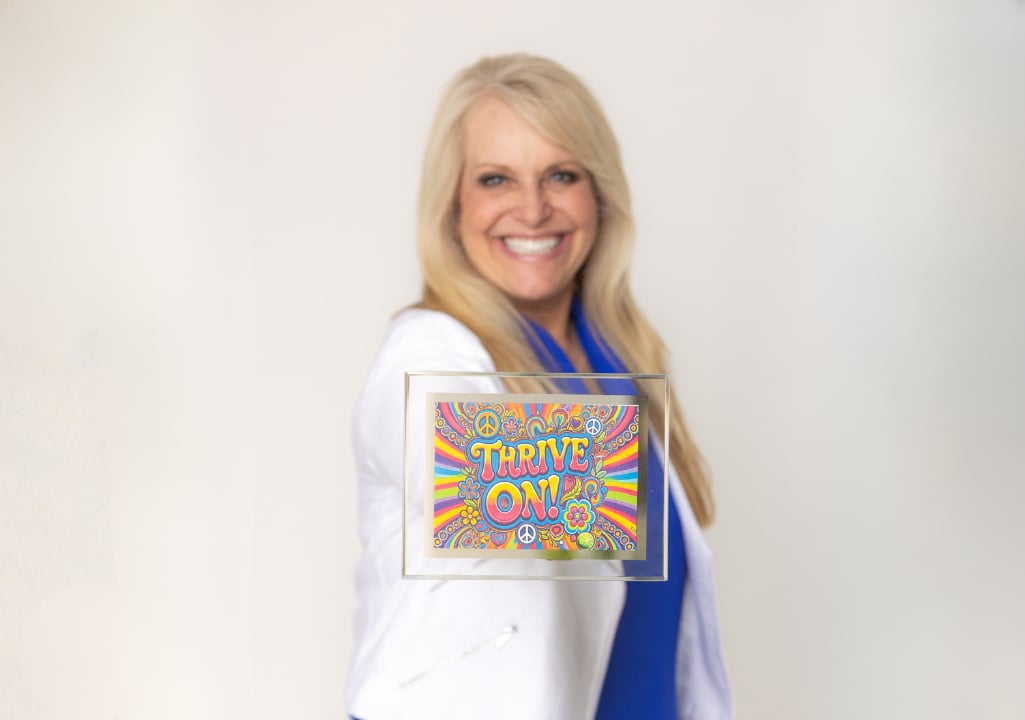 “Sharla Ellis holding a ‘Thrive On’ sign, sharing encouragement about alignment, purpose, and beginning again.”