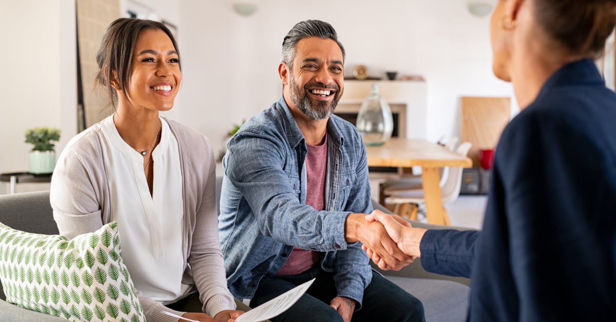 Smiling couple meeting with a real estate agent at home to plan the sale of their Downers Grove home in winter.