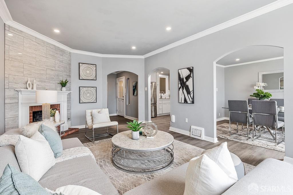 Staged living room with a tiled fireplace wall and arched opening to the dining area.
