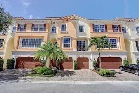 Attached peach-and-cream townhomes with red shutters, front-entry garages, and palm trees.