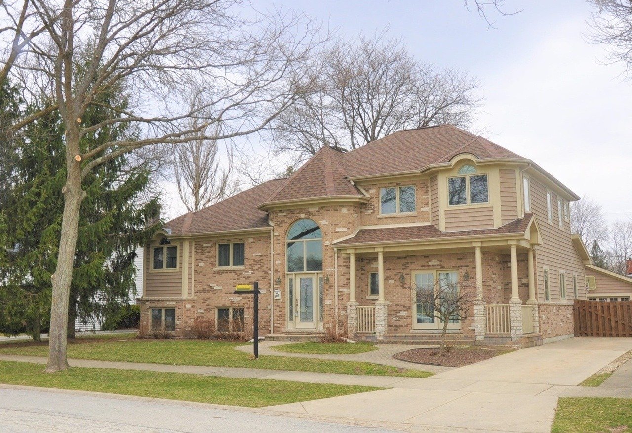 Two-story brick-and-siding house with a covered porch, arched entry window, and wide driveway.