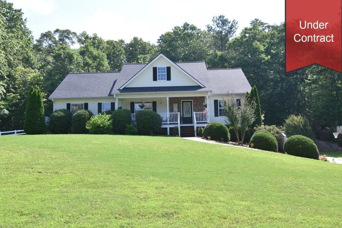 Home with a covered front porch and broad lawn, marked “Under Contract.”