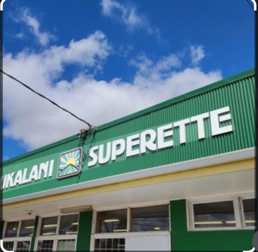 Ikalani Superette storefront with a green sign beneath a bright blue sky.