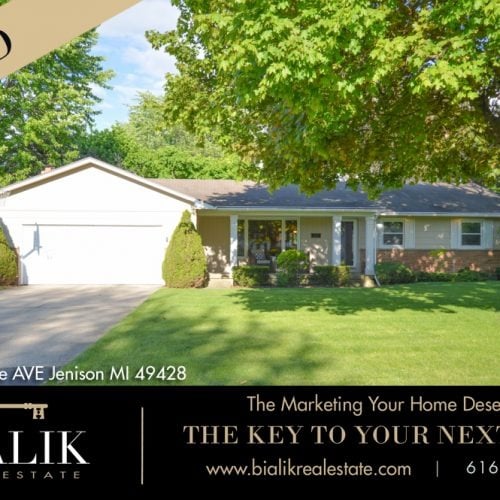 Ranch-style home with an attached garage, brick accents, and a broad lawn beneath mature trees.