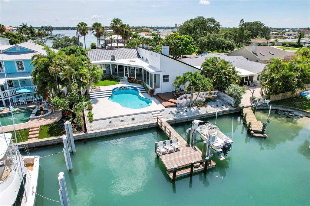 Waterfront home with a pool, canal-facing dock, and boat lift.