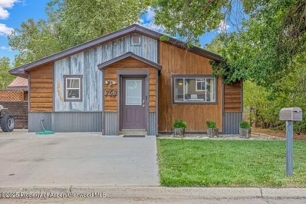 Single-story Craig home with mixed wood and metal siding, a covered entry, driveway, and small front lawn.