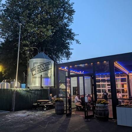 The Bronx Brewery patio at night, with a glass entrance and large brewing tank.