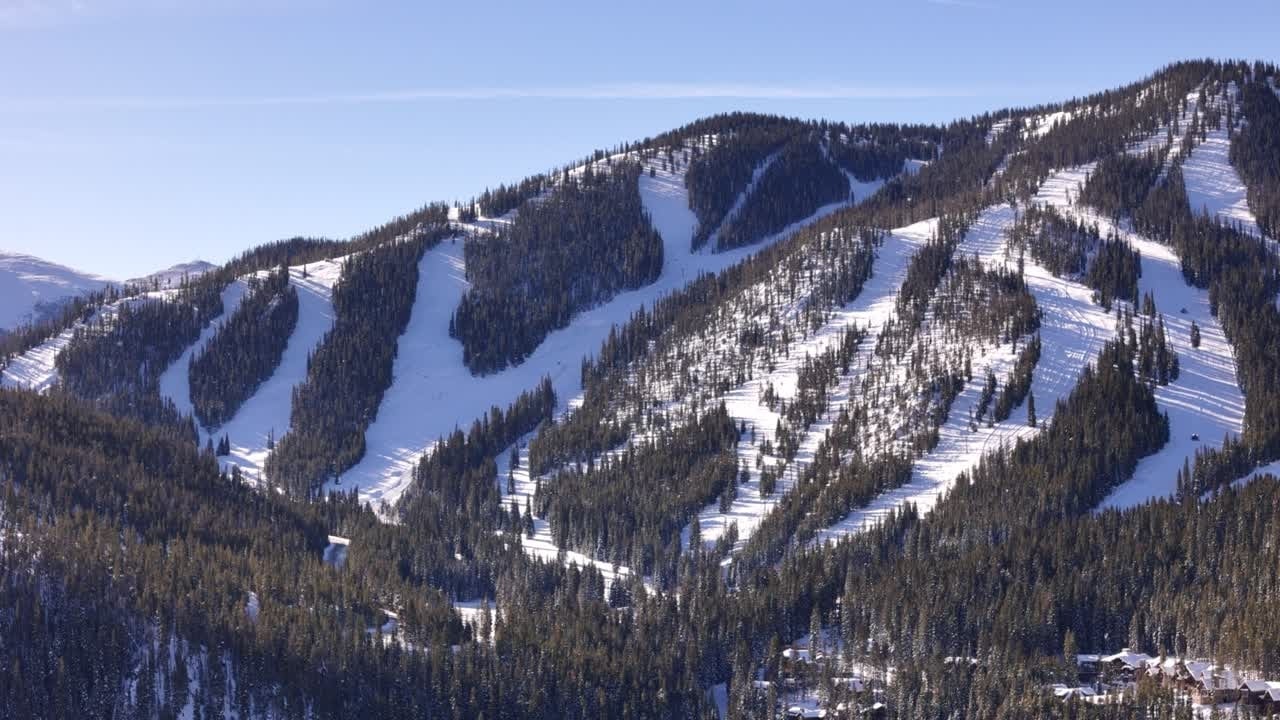 Snowy ski runs wind through evergreen forest across a Winter Park mountain.