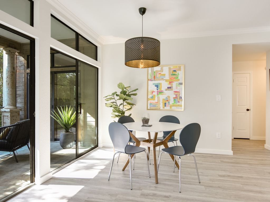 Dining area with sliding glass doors to a covered patio and greenbelt views at 1000 Liberty Park Drive #203, Liberty Park Condominiums, Westlake, Austin, TX 78746.