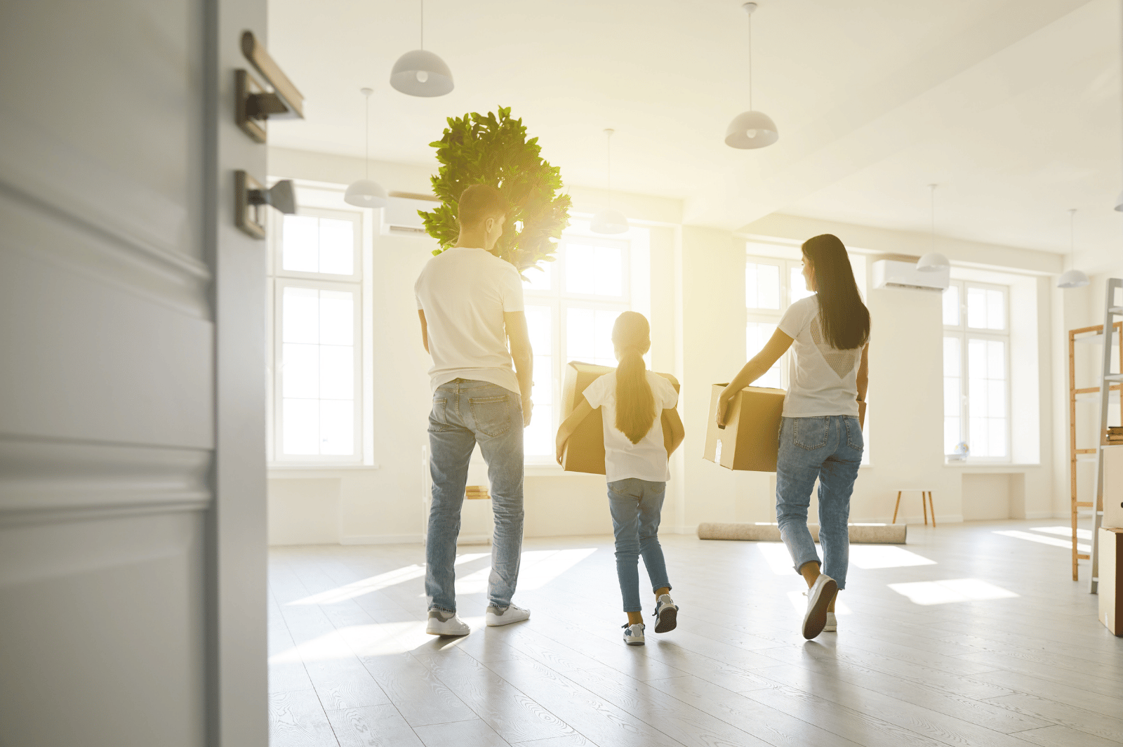 Family carrying boxes into a bright, mostly empty home