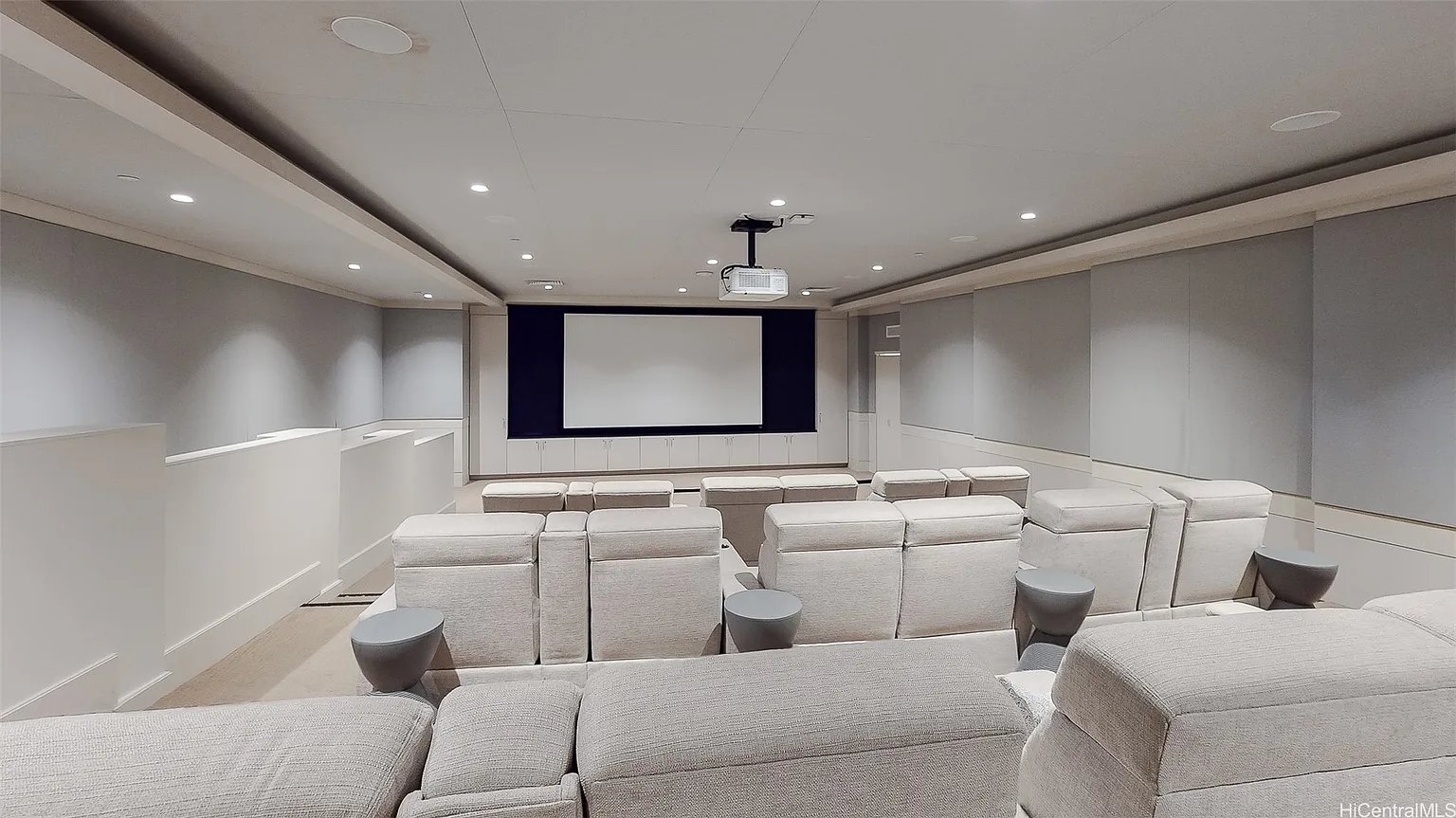 Screening room with rows of pale seats facing a large projection screen.