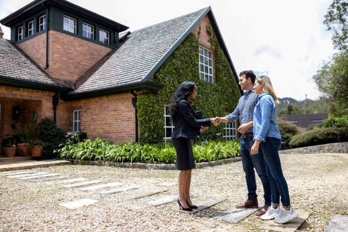 Real estate professional meeting prospective homebuyers outside residential property