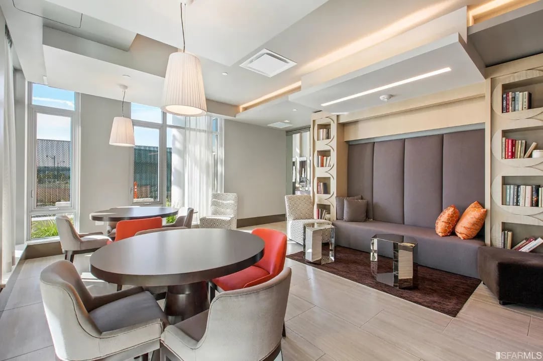 Arden Residences luxury resident lounge with modern seating areas, round dining table, built-in bookshelves, and pendant lighting in Mission Bay