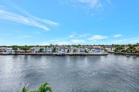 Waterfront homes along a canal, seen across rippling water beneath a bright blue sky.