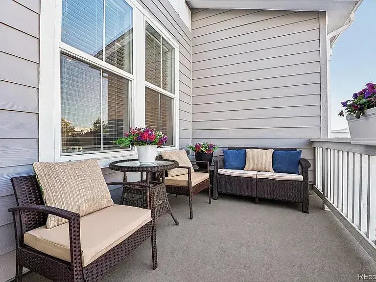 Private and serene front porch at 2092 S Upham Way, Denver, CO 80227, featuring a cozy wicker patio set with cushions.