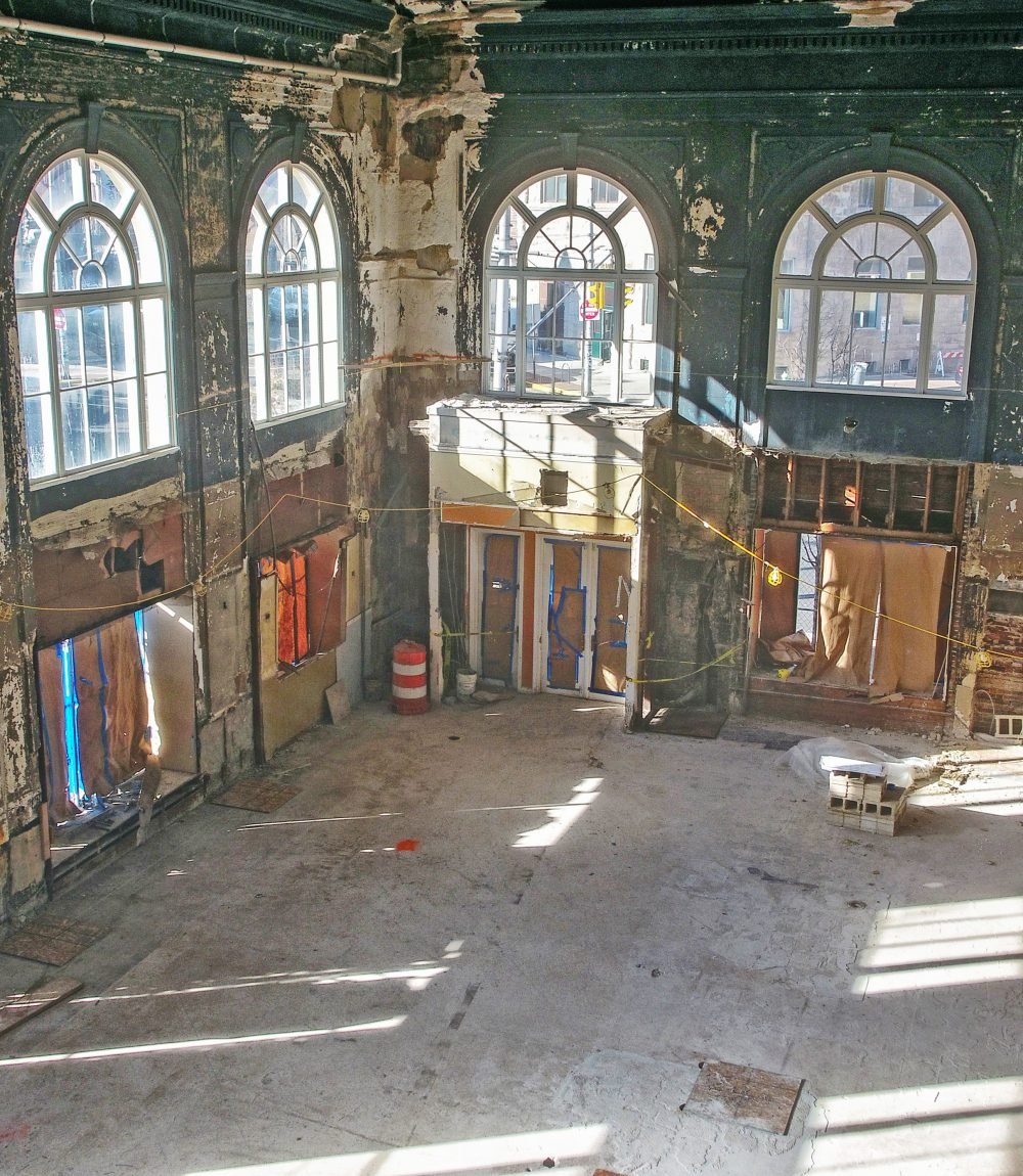 Unfinished interior with tall arched windows, exposed walls, and a bare concrete floor.